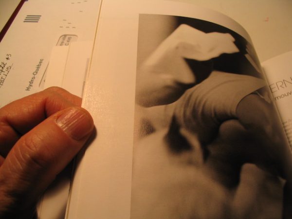 Hand weighing down book while holding single page